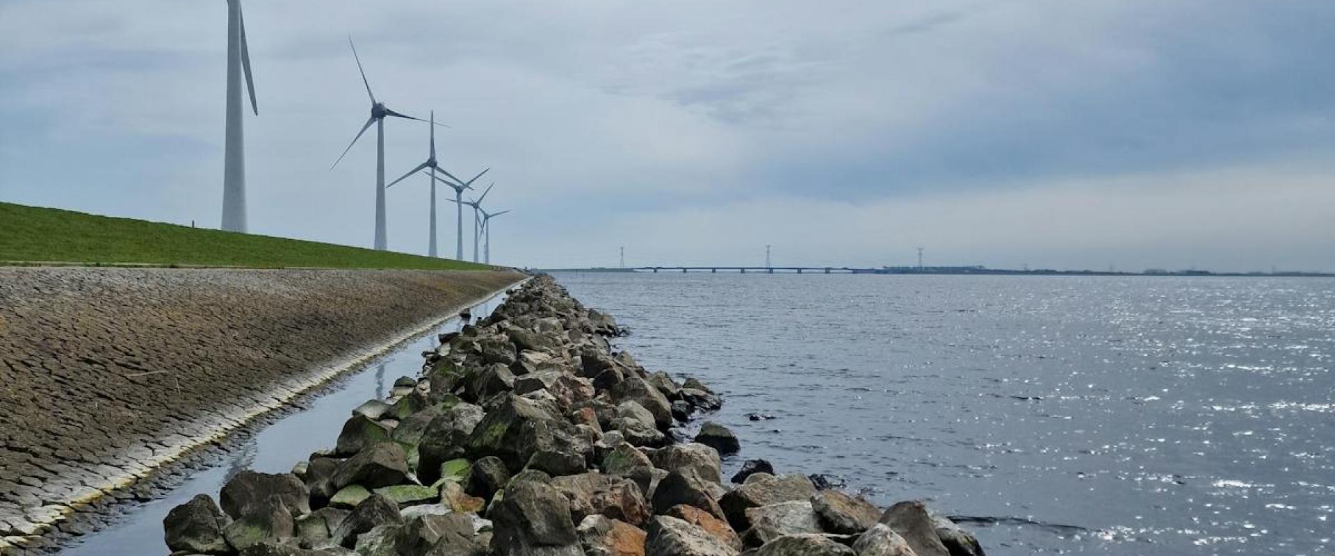 Scenic view of wind turbines by the rocky shore in Nagele, Netherlands.