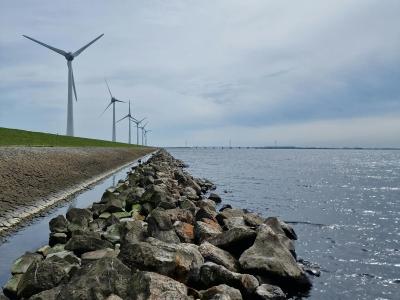 Scenic view of wind turbines by the rocky shore in Nagele, Netherlands.