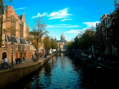 Charming view of Amsterdam's canals, architecture, and vibrant urban life under a clear blue sky.