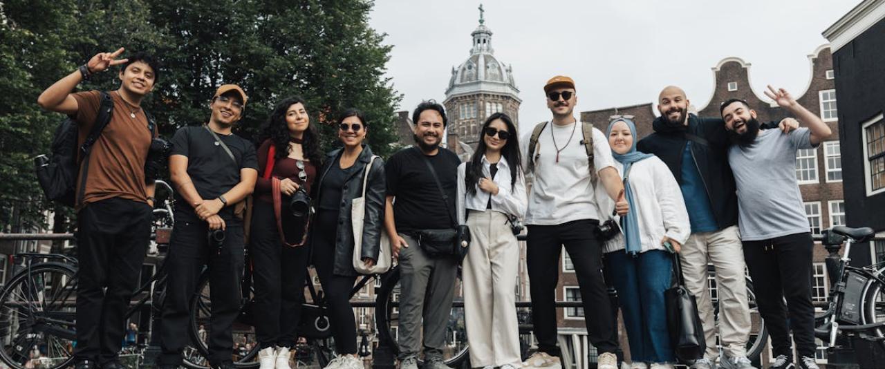 A joyful group of tourists posing in front of a scenic Amsterdam background, capturing the essence of travel and urban exploration.