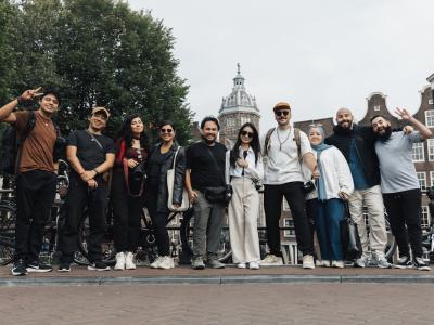 A joyful group of tourists posing in front of a scenic Amsterdam background, capturing the essence of travel and urban exploration.