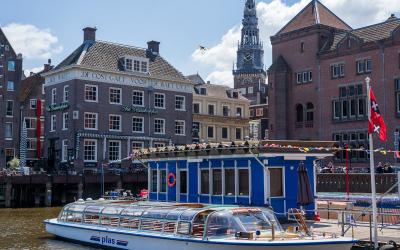 Daytime view of a canal boat and historic architecture in Amsterdam.