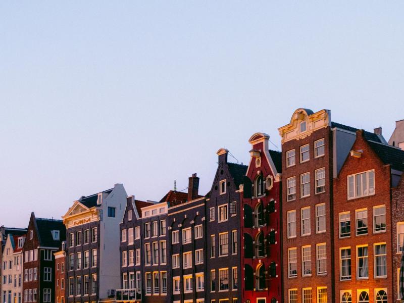 Picturesque Amsterdam canal lined with iconic traditional houses during a serene sunset.