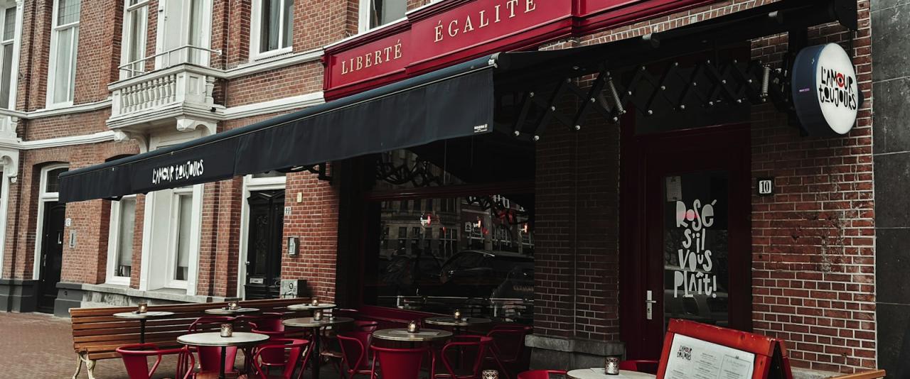 Cafe with red awnings and outdoor terrace tables on a brick street in a Dutch town