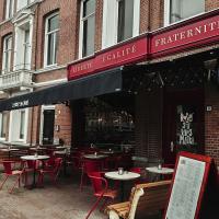 Cafe with red awnings and outdoor terrace tables on a brick street in a Dutch town