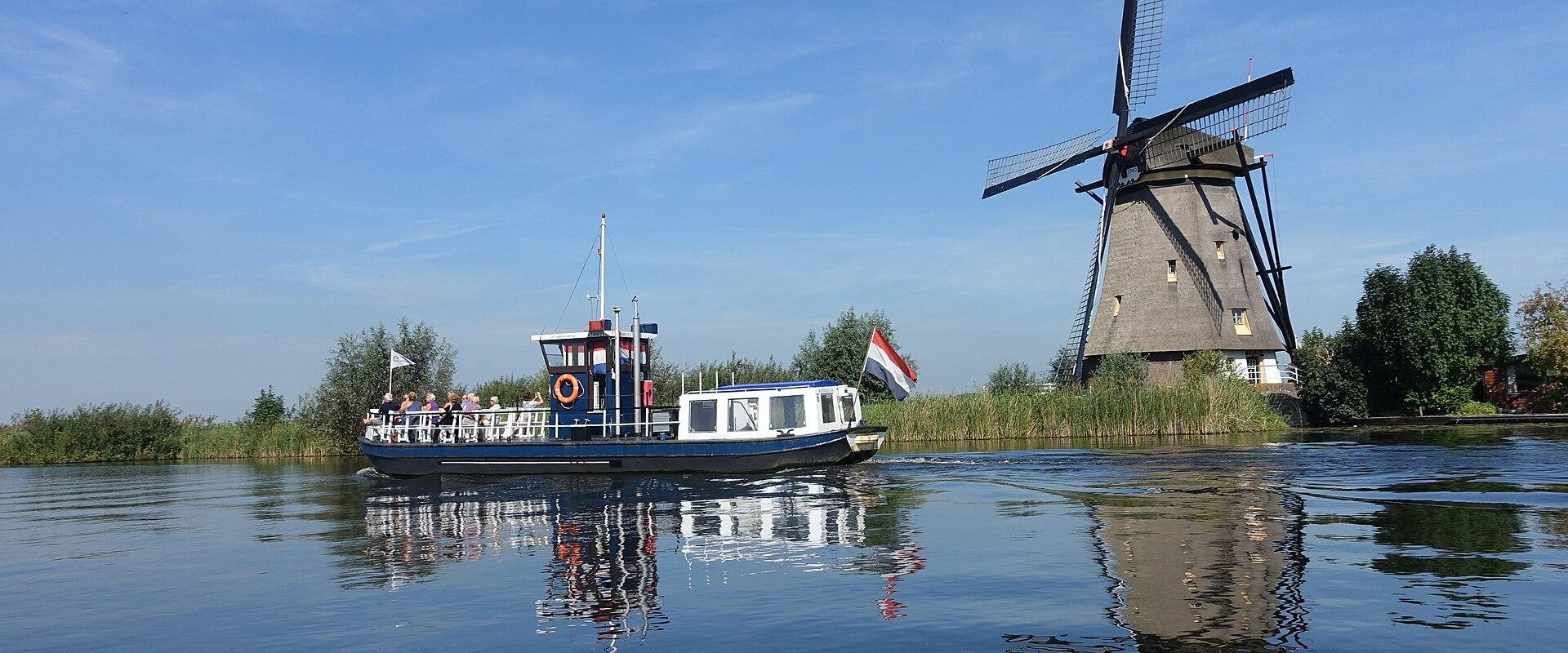 A tour boat passing a windmill on the Kinderdijk canals