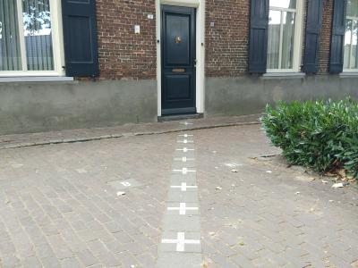 Border crosses and NL/B markings painted on the pavement at a house doorway in Baarle, where the Belgian-Dutch border runs through the town