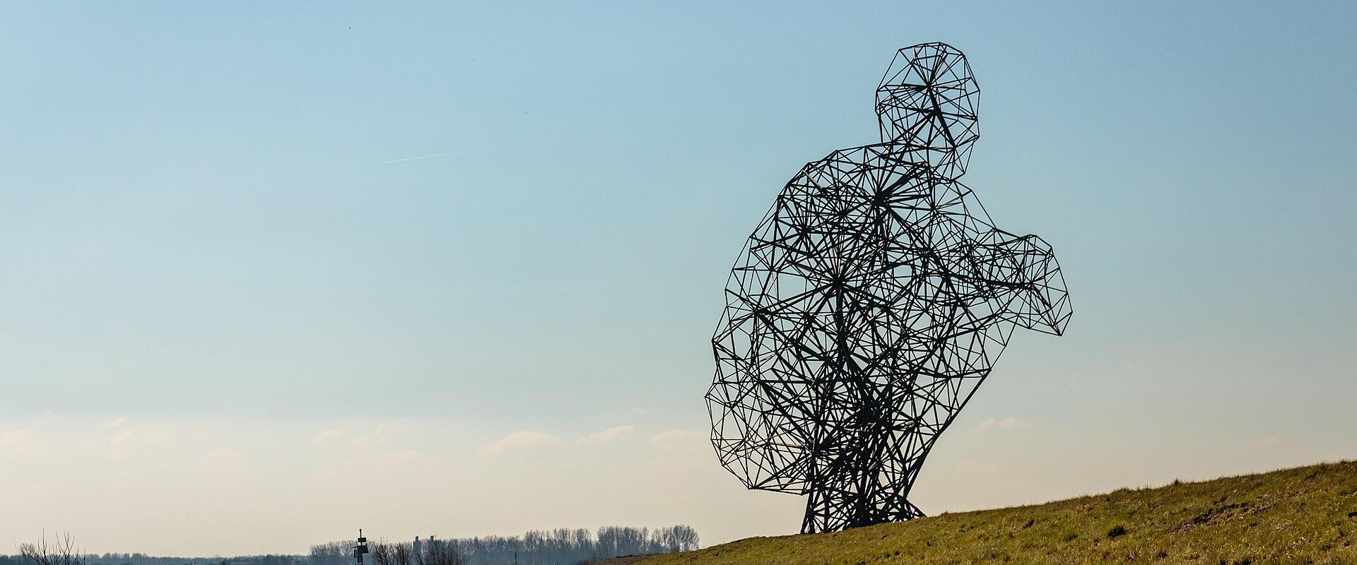 Antony Gormley's crouching steel figure Exposure on the dyke at Lelystad