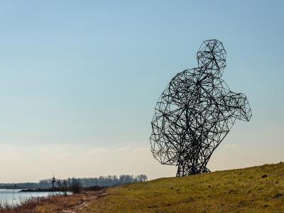 Antony Gormley's crouching steel figure Exposure on the dyke at Lelystad