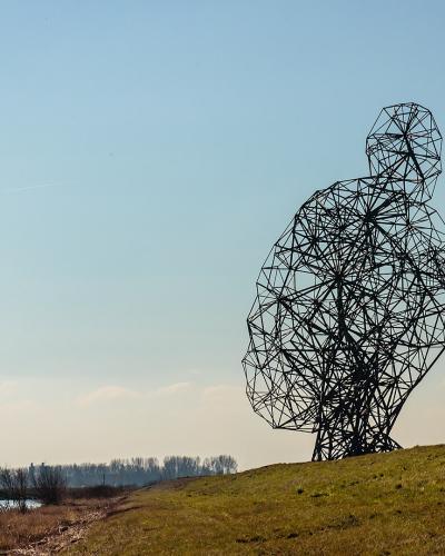Antony Gormley's crouching steel figure Exposure on the dyke at Lelystad
