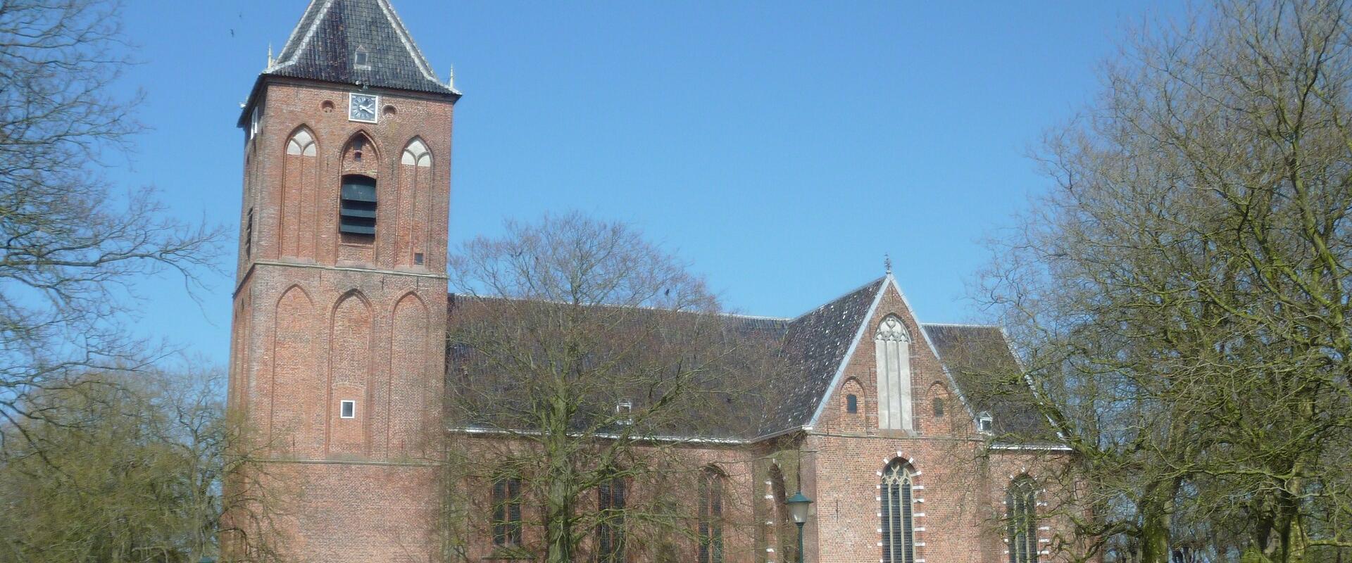 The medieval brick Hippolytuskerk in Middelstum with its saddleback-roofed tower under a blue sky