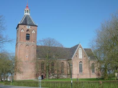 The medieval brick Hippolytuskerk in Middelstum with its saddleback-roofed tower under a blue sky