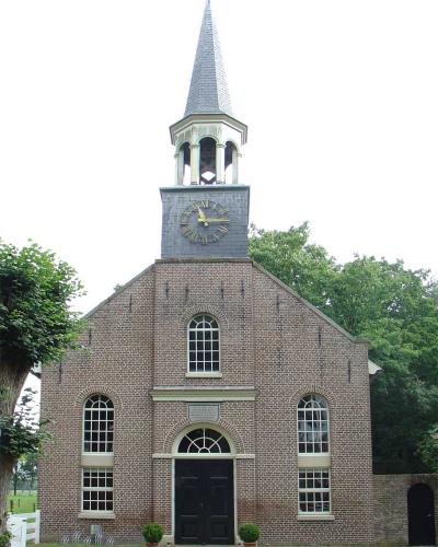 A front-facing photograph of a brick church with a central clock tower and spire, featuring arched windows and a plaque above the entrance.
