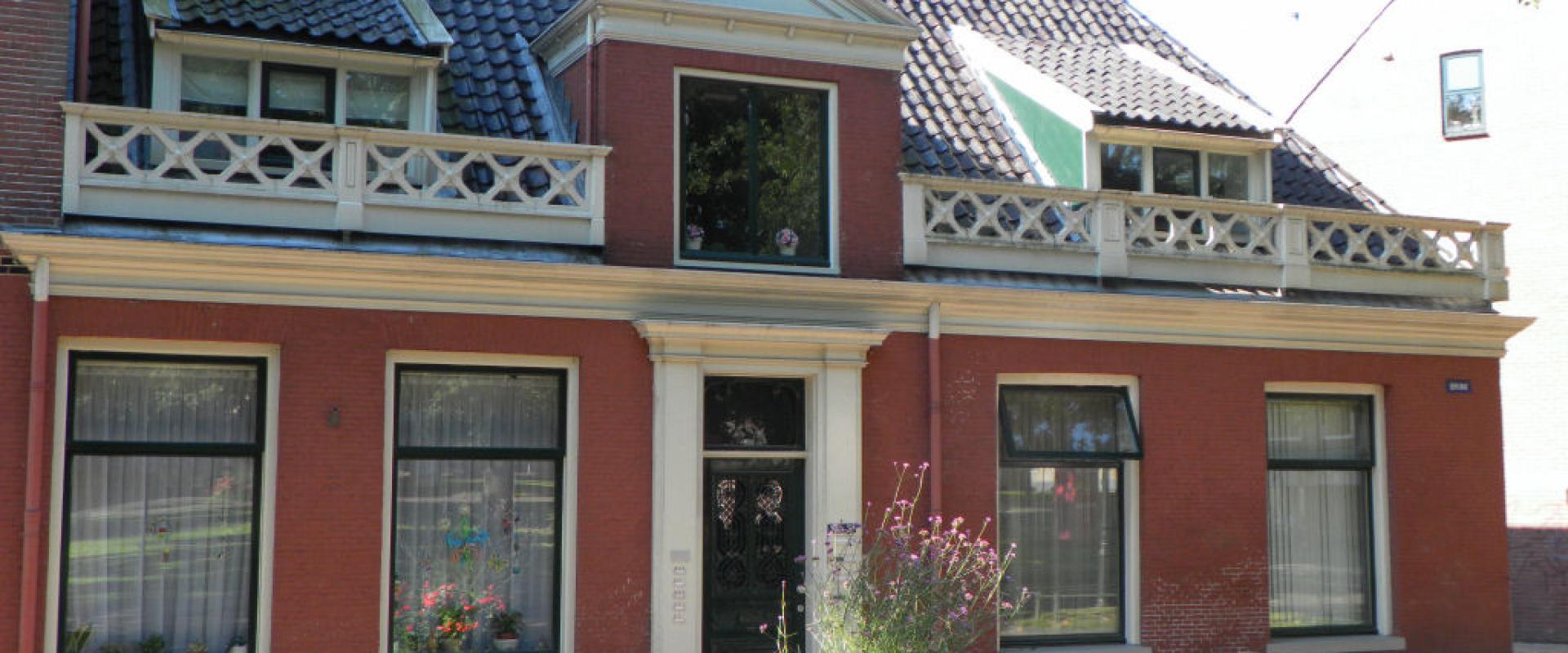 A red-brick historic townhouse with a balustraded balcony on the Brink in Assen
