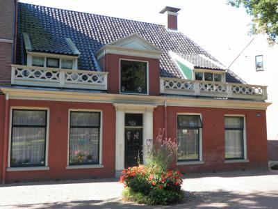 A red-brick historic townhouse with a balustraded balcony on the Brink in Assen