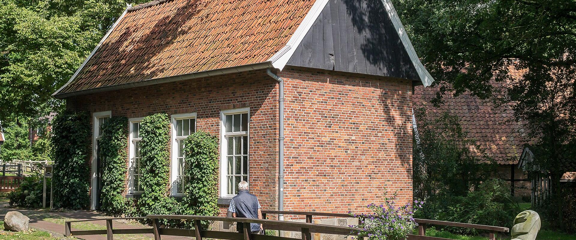 The brick Hofkamer farmhouse with a tiled roof and a wooden footbridge at the Openluchtmuseum Ootmarsum