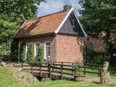The brick Hofkamer farmhouse with a tiled roof and a wooden footbridge at the Openluchtmuseum Ootmarsum