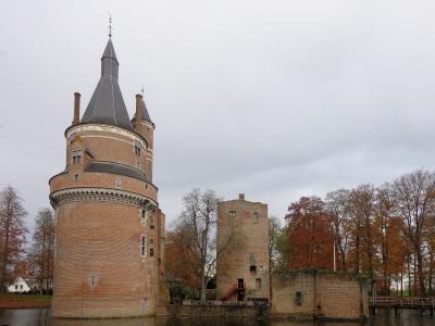 The round red-brick tower of Kasteel Duurstede in Wijk bij Duurstede, Netherlands, rising above the castle moat among autumn trees